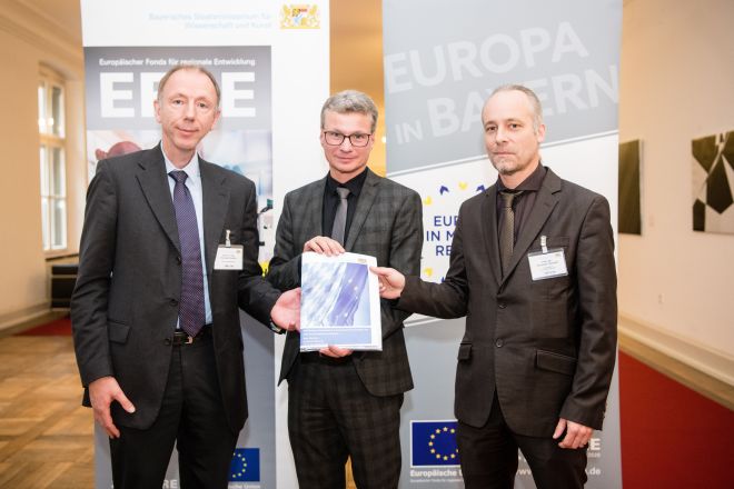 Wissenschaftsminister Bernd Sibler (M.) übergibt den EFRE-Förderbescheid für GlasTAOO4.0 an Prof. Dr. Christian Laforsch (r.) und Prof. Dr.-Ing. Thorsten Gerdes, der das Verbundprojekt mit der TH Deggendorf koordiniert.